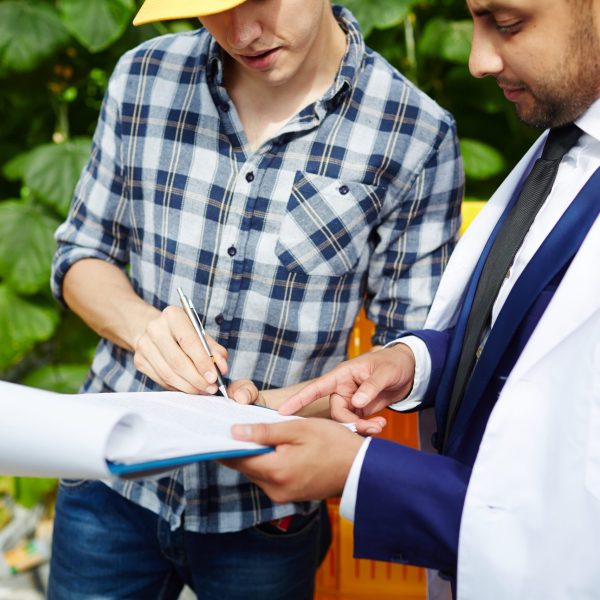 Greenhouse worker signing paper where his employer showing